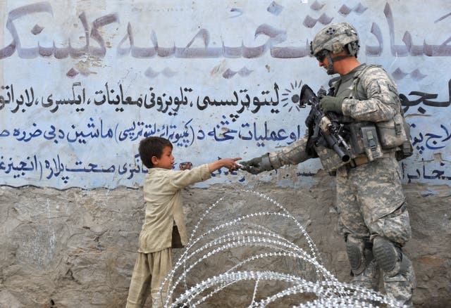 <p>US soldier  presents a gift to an Afghan child during a patrol at Khogiani in Langarhar in 2010</p>
