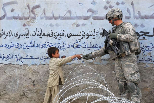 Un soldado estadounidense de la 4a División de Infantería 4 Brigada Alpha Company presenta un regalo a un niño afgano durante una patrulla en Khogiani en Langarhar