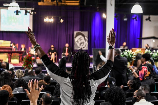 <p>A woman raises her hands as she prays during the funeral of Daunte Wright </p>