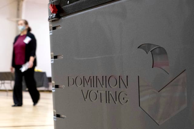 A worker passes a Dominion Voting ballot scanner while setting up a polling location at an elementary school in Gwinnett County, Georgia