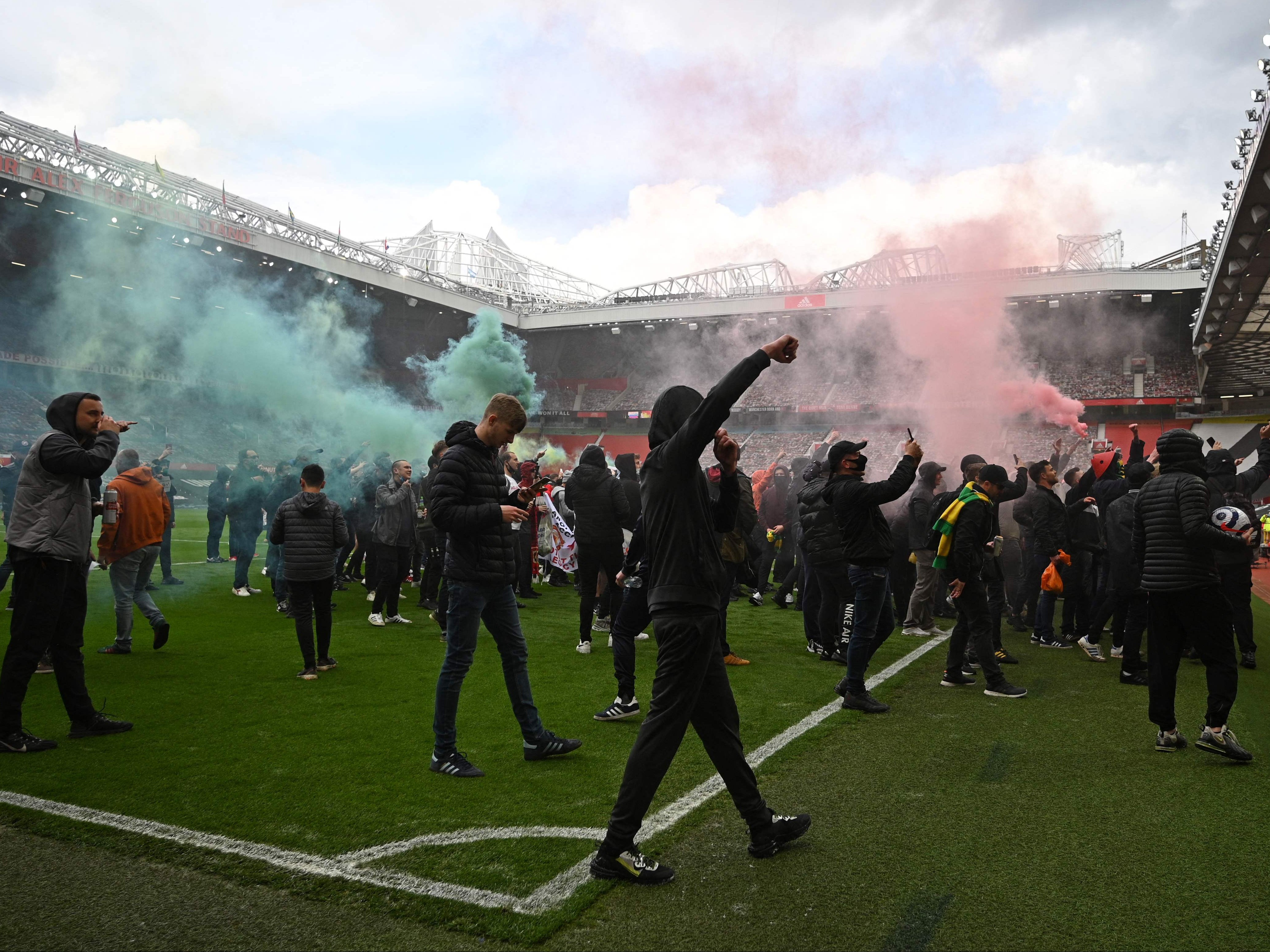 Fans set off flares on the pitch at Old Trafford before the game with Liverpool was called off