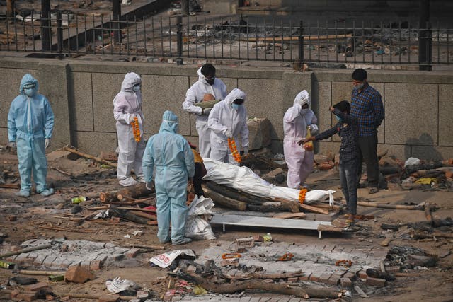 <p>Relatives and friends wearing personal protective equipment (PPE) suits prepare the body of a victim who died due to the Covid-19</p>