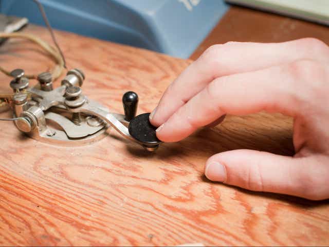 A man works a telegraph key at a desk.