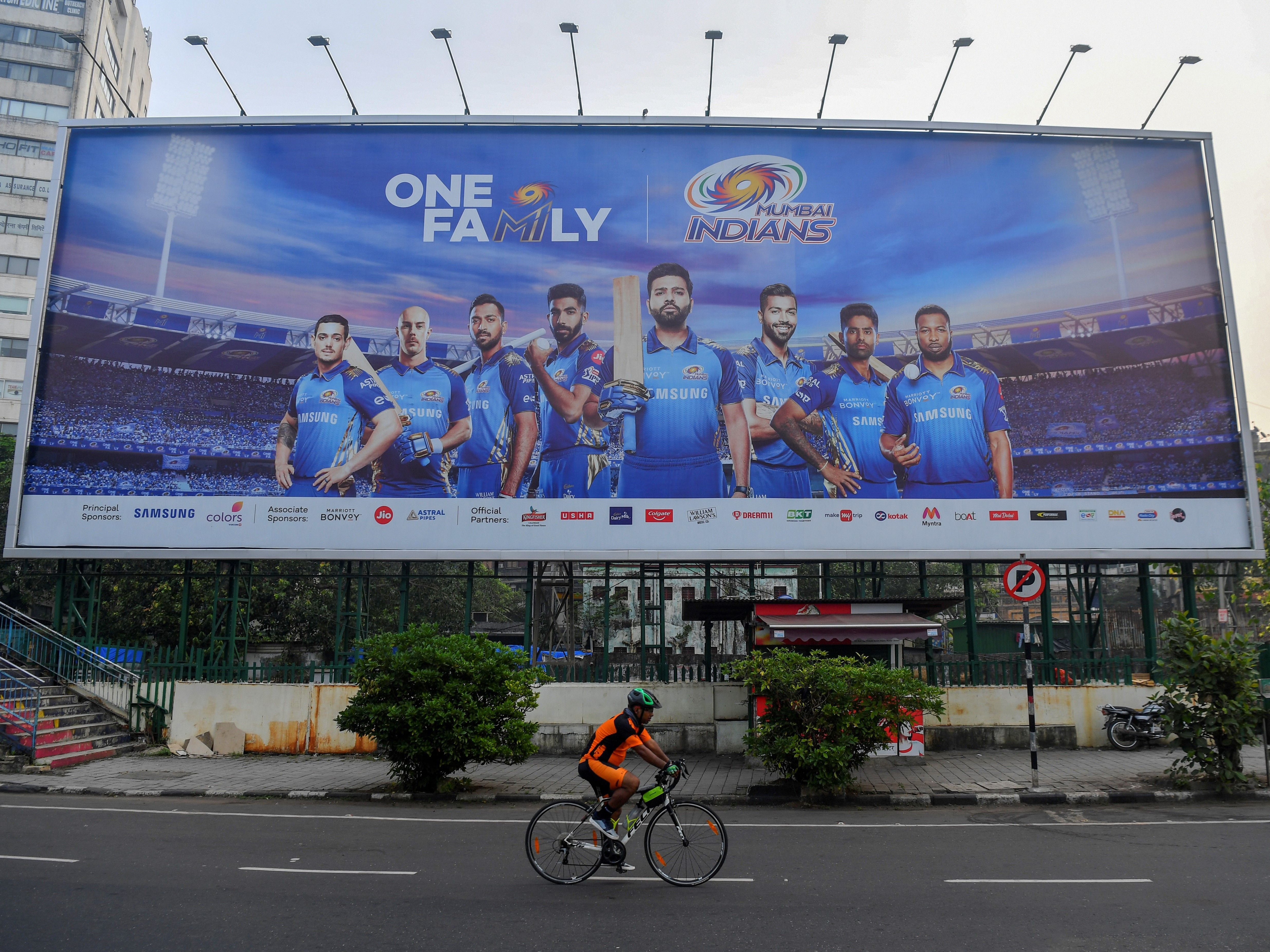 A cyclist rides past a hoarding of Mumbai Indians cricketers of the Indian Premier League