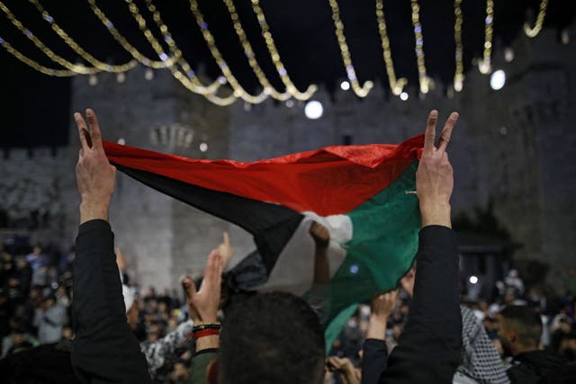 <p>Palestinian protesters wave the national flag outside the Damascus Gate in Jerusalem’s Old City on 26 April, 2021</p>