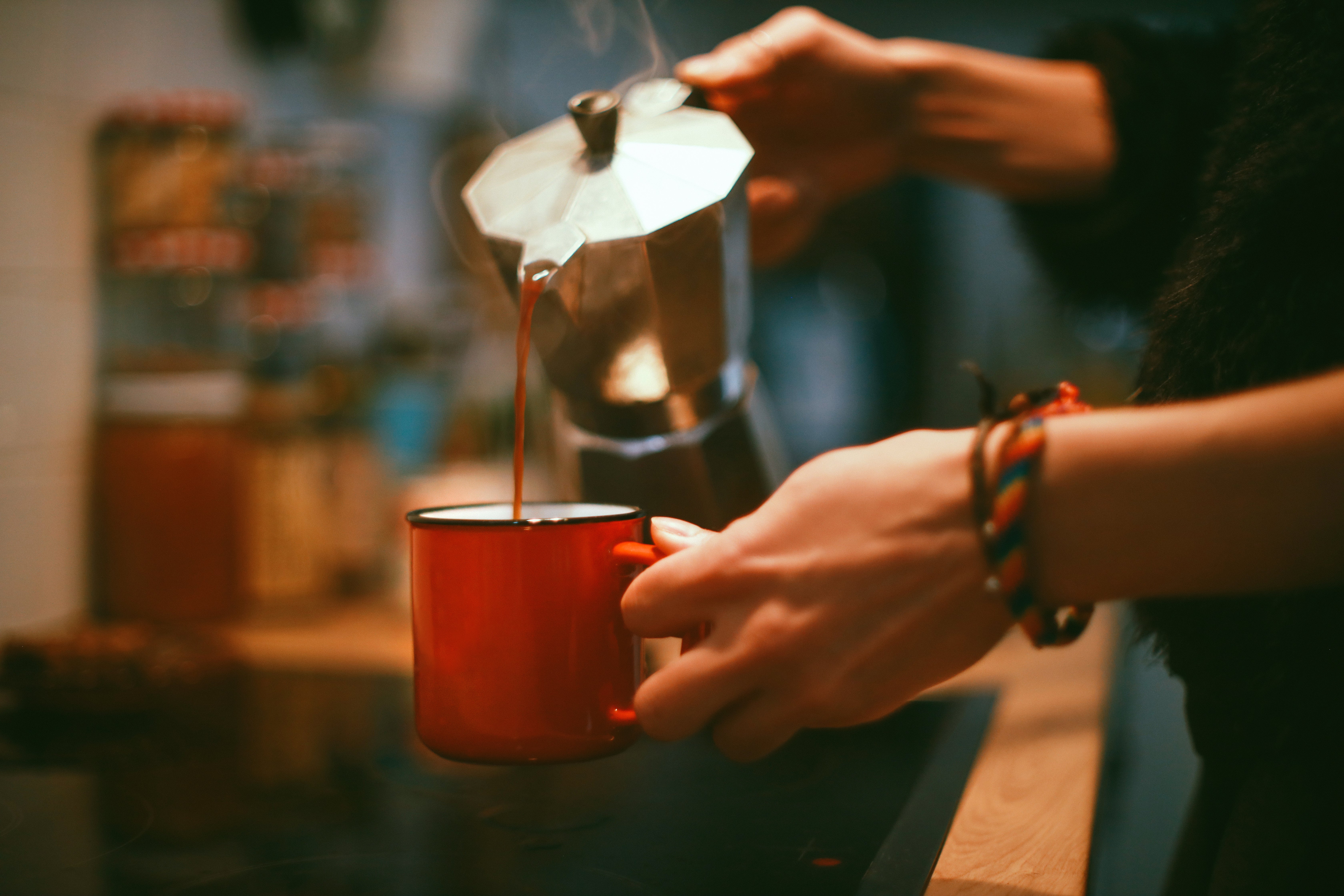 A woman’s hands while she’s pouring coffee into a cup