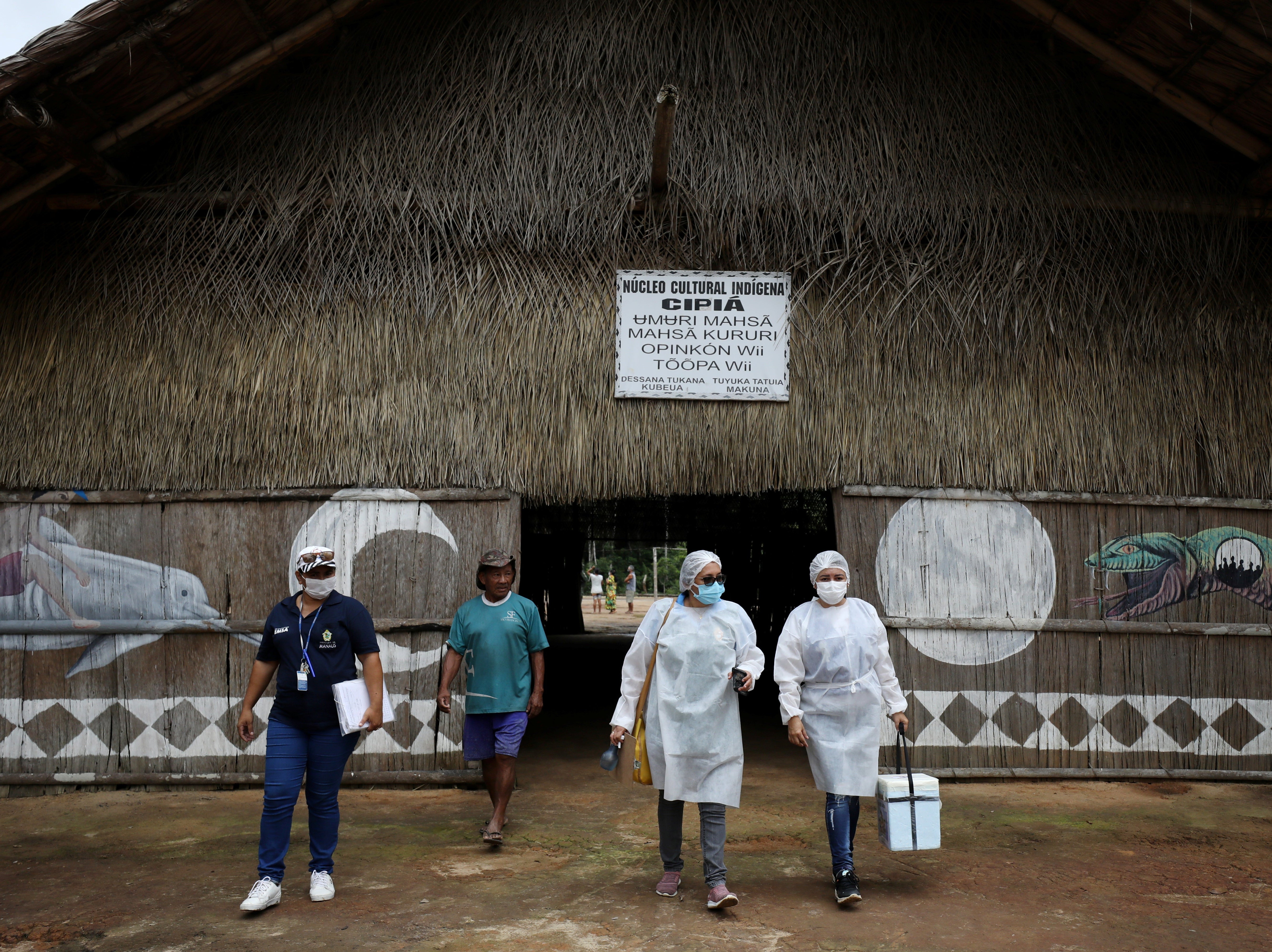 Municipal health workers leave an Indigenous hut after administering the AstraZeneca Covid vaccine in the Sustainable Development Reserve of Tupe
