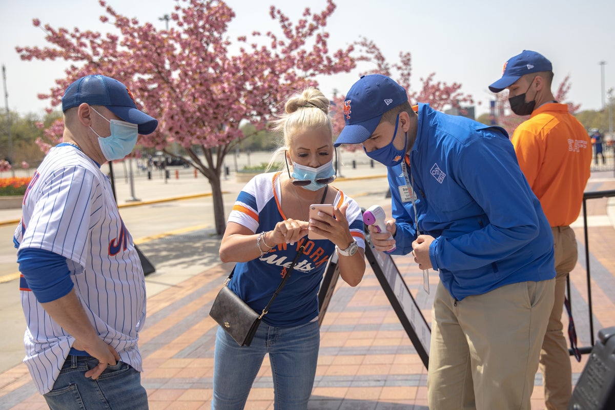 A fan shows a vaccine passport on her phone as she arrives for a New York Mets game