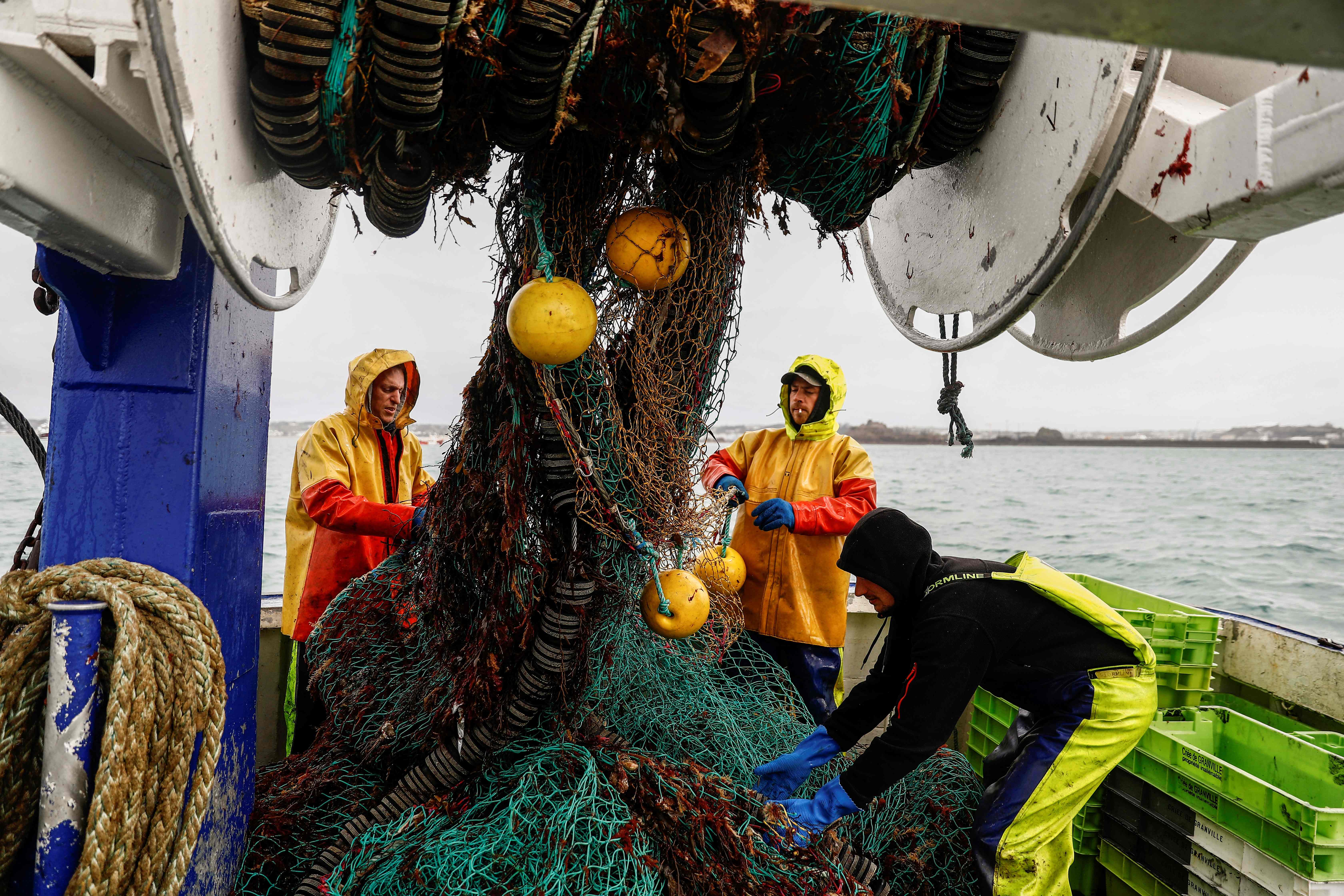 French fishermen gather in a net on their vessel near the port of Saint Helier, Jersey