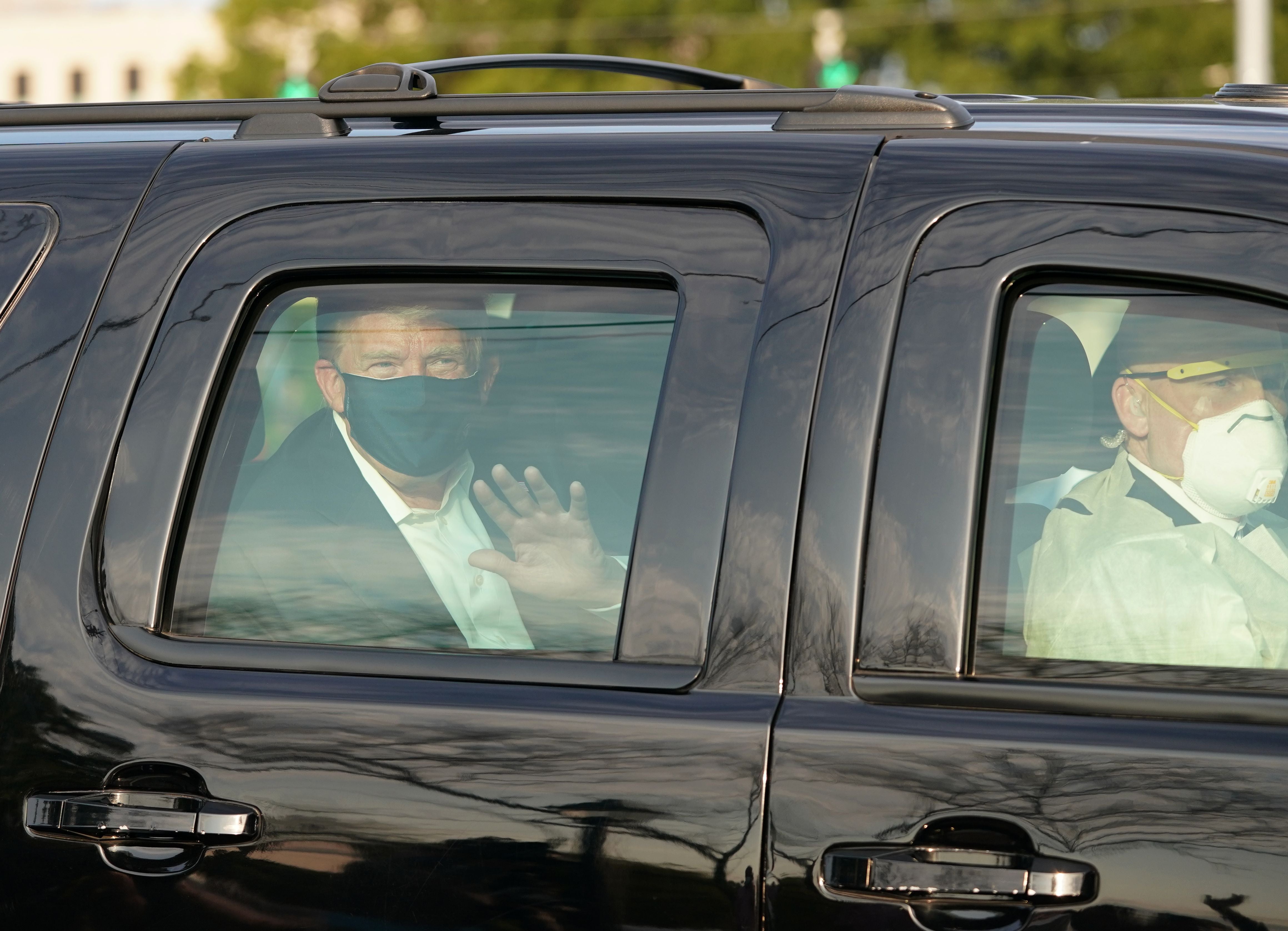 Donald Trump waves from the back of a car in a motorcade outside of Walter Reed Medical Center in Bethesda, Maryland on October 4, 2020.
