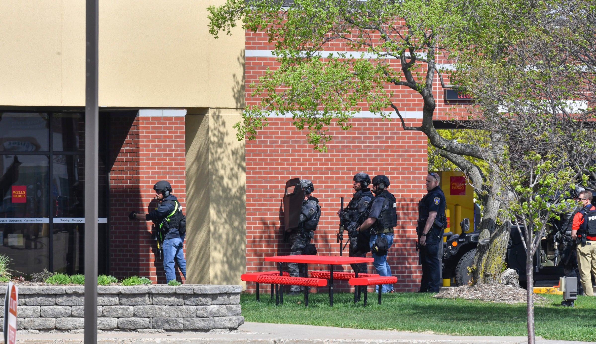 Officers gather near an entrance at the Wells Fargo branch Thursday May 6, 2021, in south St. Cloud, Minnesota. Police were on the scene Thursday of a reported bank robbery with hostages