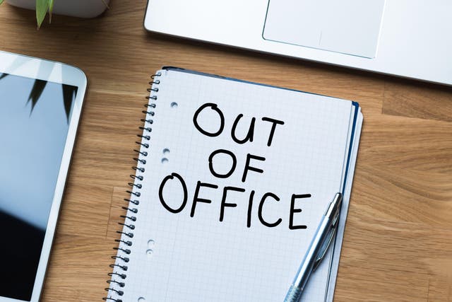 'Out of office' written on notepad on desk