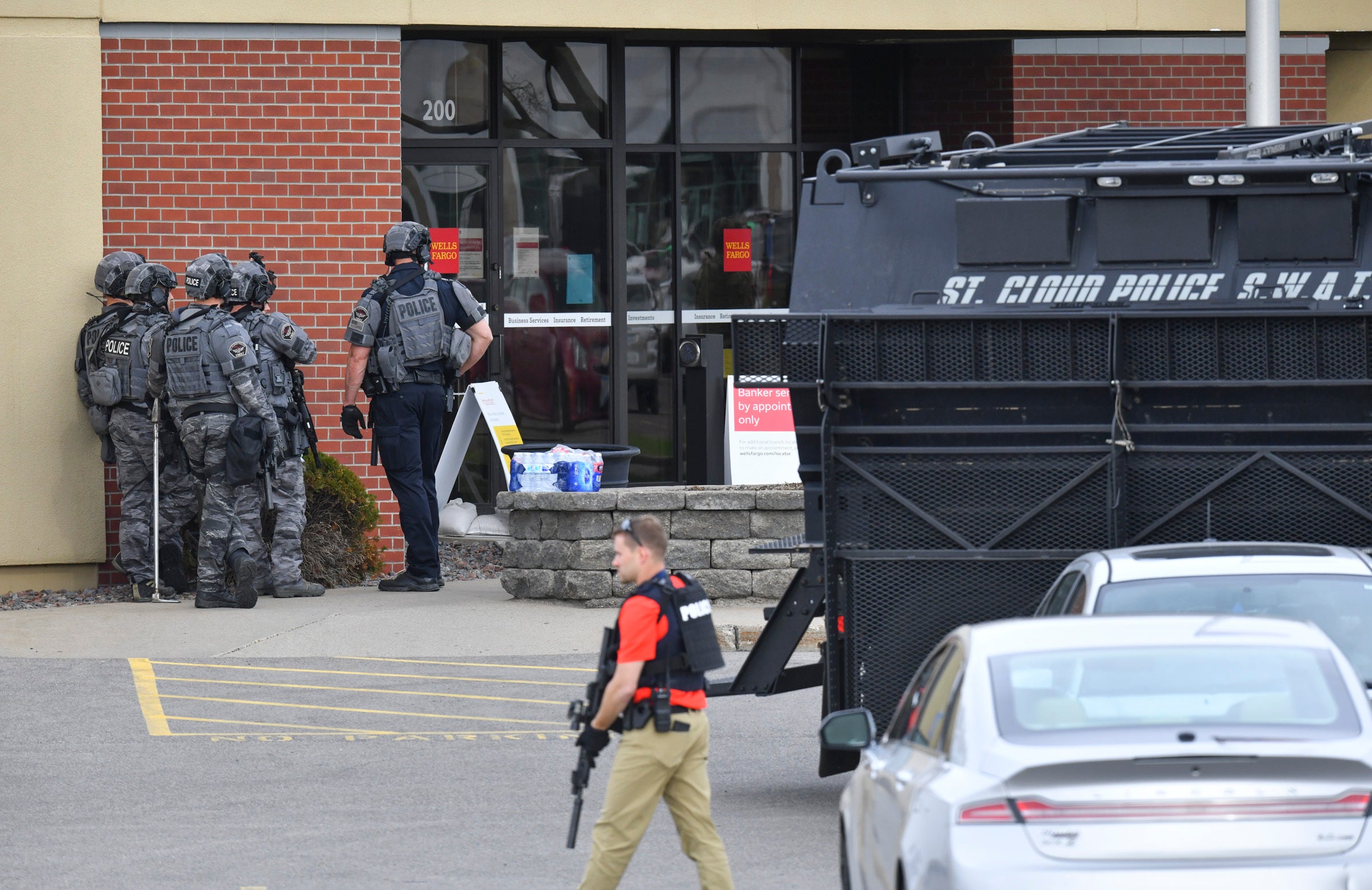 Officers stand near an entrance to the Wells Fargo branch Thursday 6 May 2021, in south St Cloud, Minnesota following a hostage situation