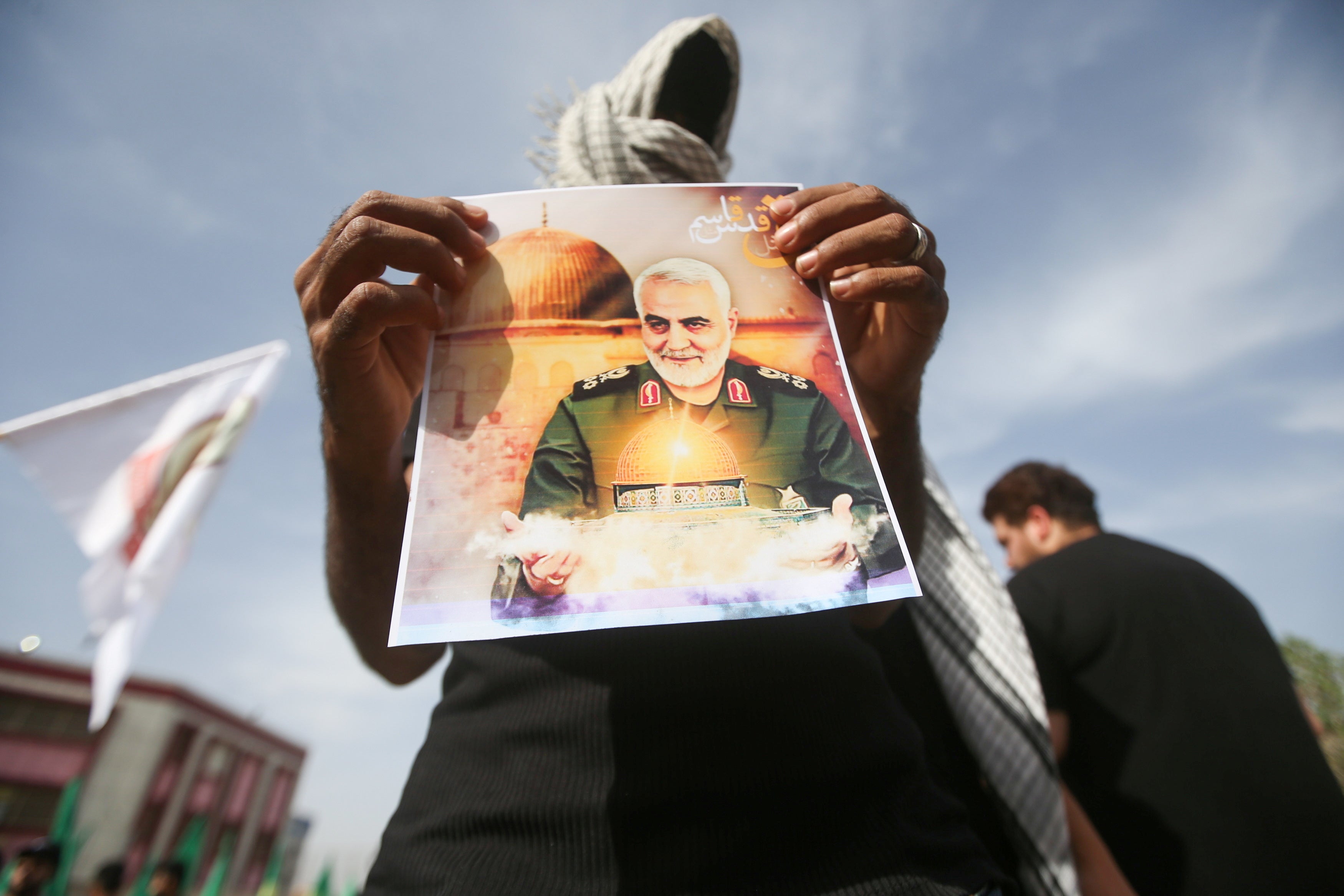 A militia member shows a picture of Qassem Soleimani, whose death has inflamed tensions