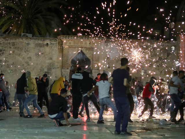 Palestinians react as Israeli police fire stun grenades during clashes at the compound that houses Al-Aqsa Mosque