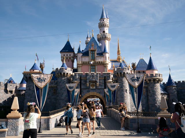 Los visitantes salen del Castillo de la Bella Durmiente en Disneyland en Anaheim, California, el 30 de abril de 2021