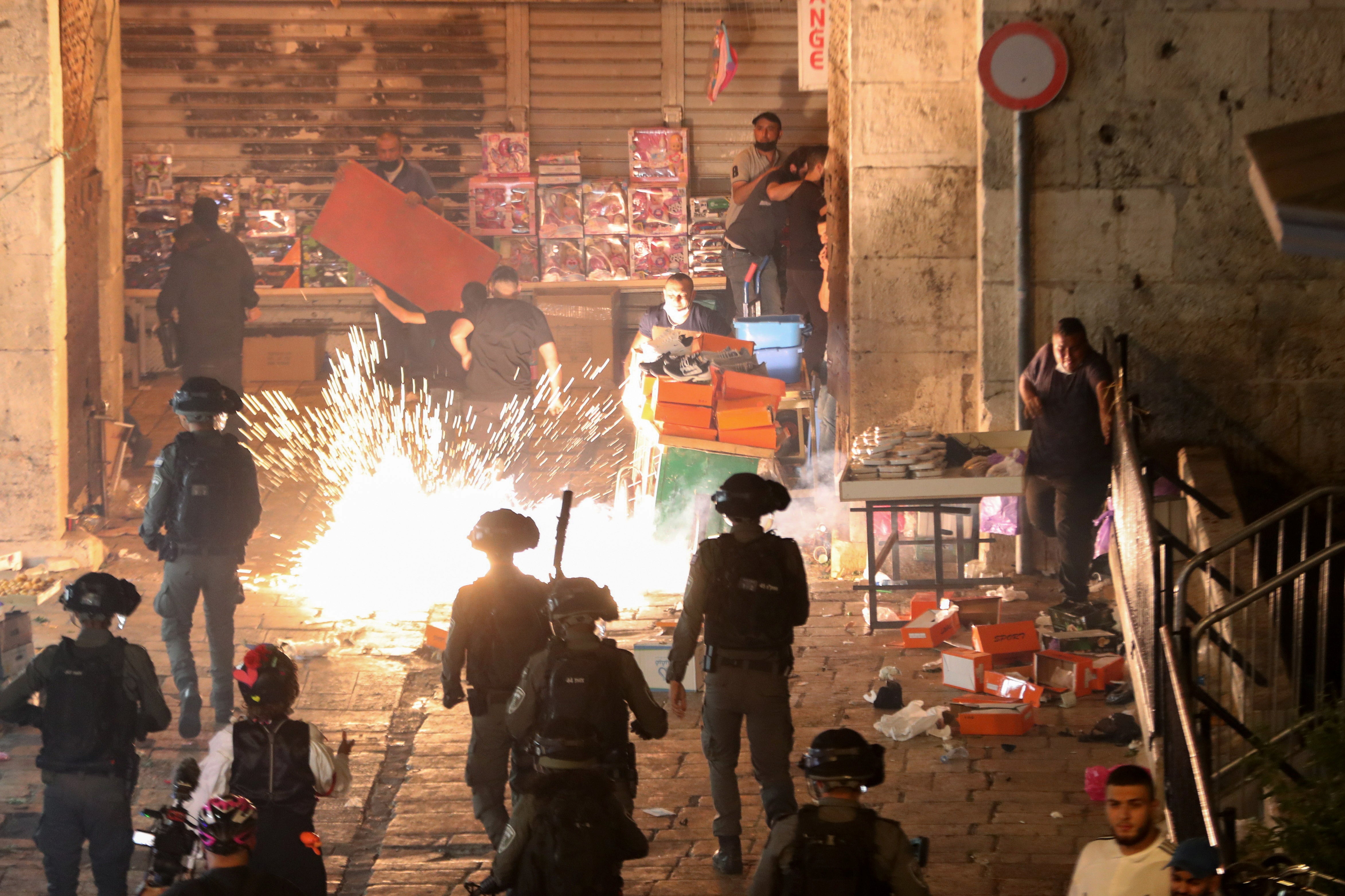 Palestinians react as Israeli police fire a stun grenade during clashes at Damascus Gate