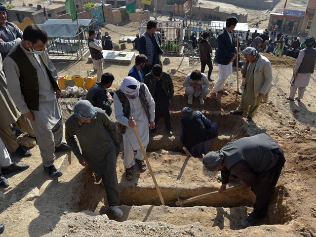 Shiite mourners and relatives dig graves for schoolgirls who died in multiple blasts outside a school in Kabul
