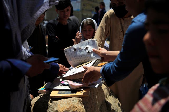 <p>Afghans go through belongings left behind after deadly bombings on Saturday near a school in Kabul, Afghanistan, Sunday, on 9 May, 2021</p>