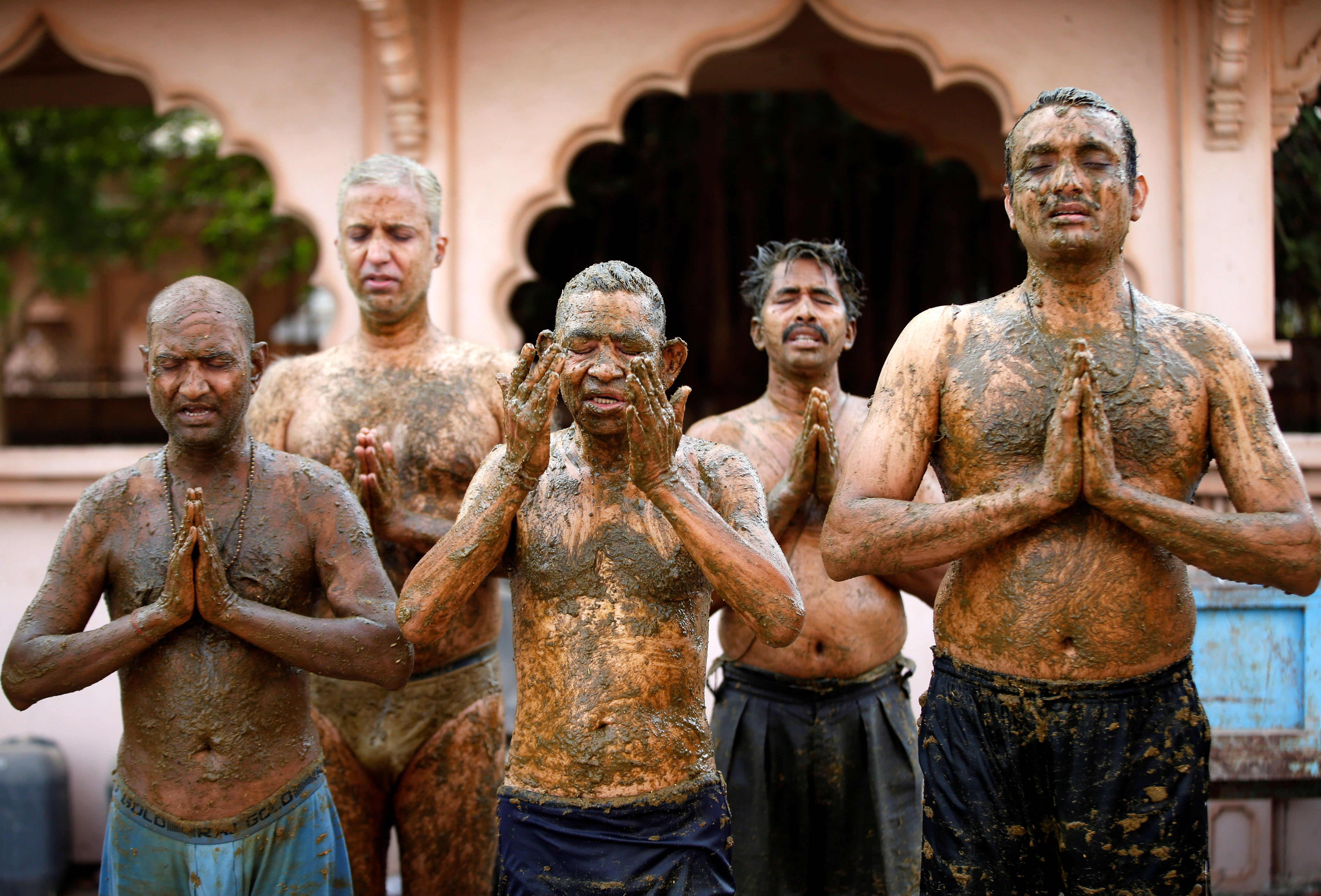 People pray after applying cow dung on their bodies during ‘cow dung therapy’ on the outskirts of Ahmedabad