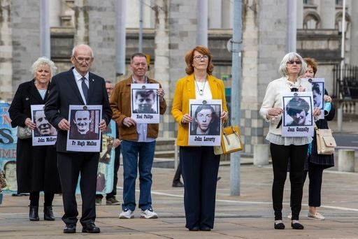 Families hold placards of their loved ones who were killed in 1971