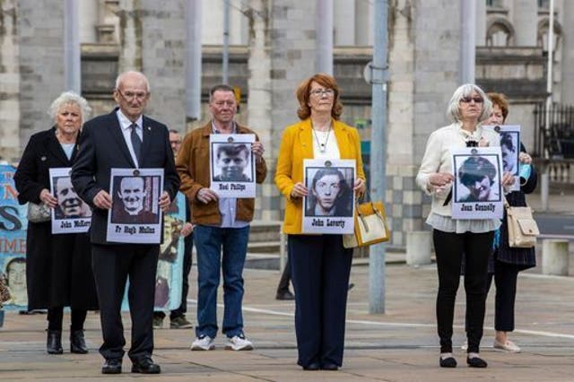 <p>Families hold placards of their loved ones who were killed in 1971</p>