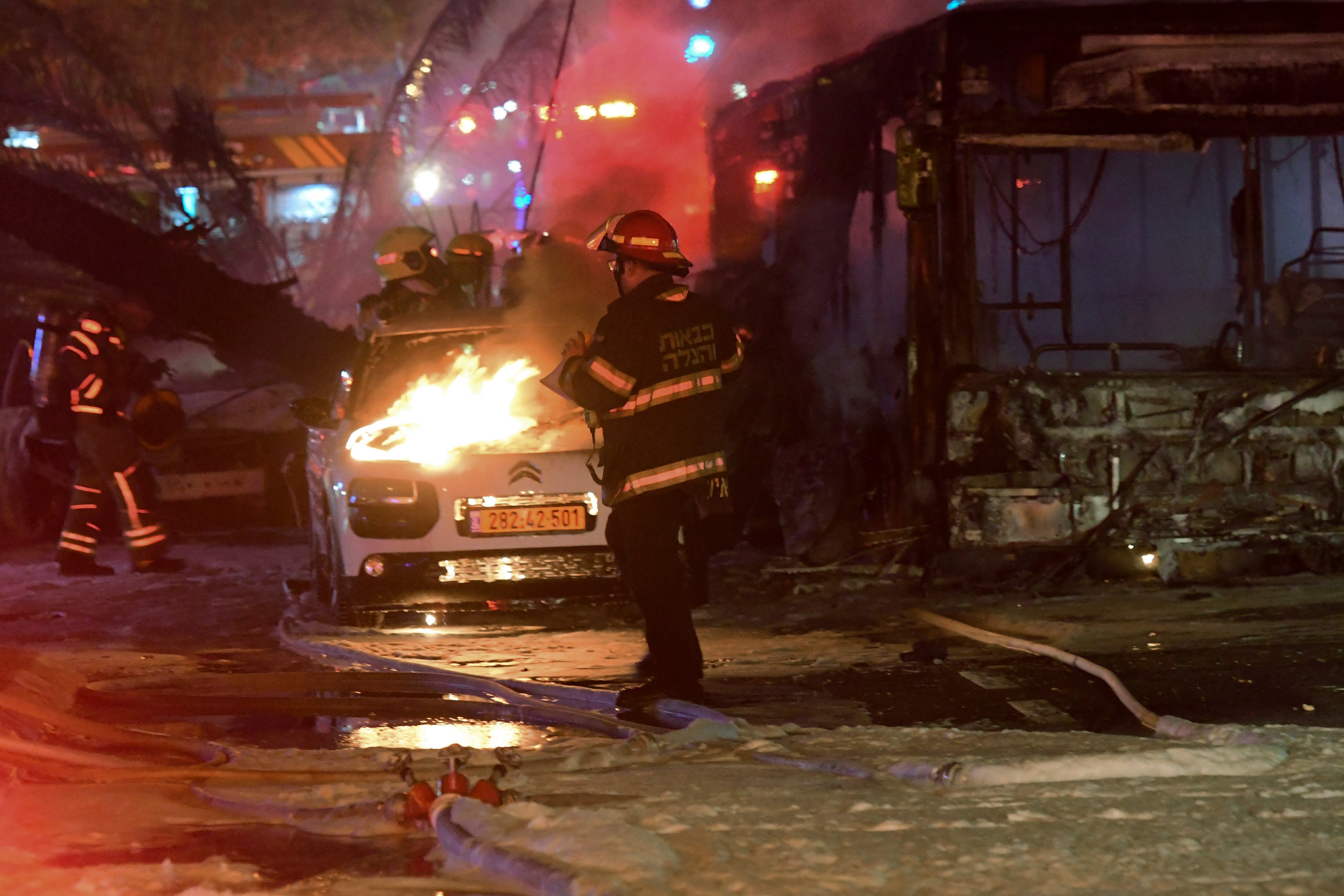 <p>An Israeli firefighter extinguishes a burning car after it was hit by a rocket fired from the Gaza Strip, at the central Israeli town of Holon, near Tel Aviv</p>