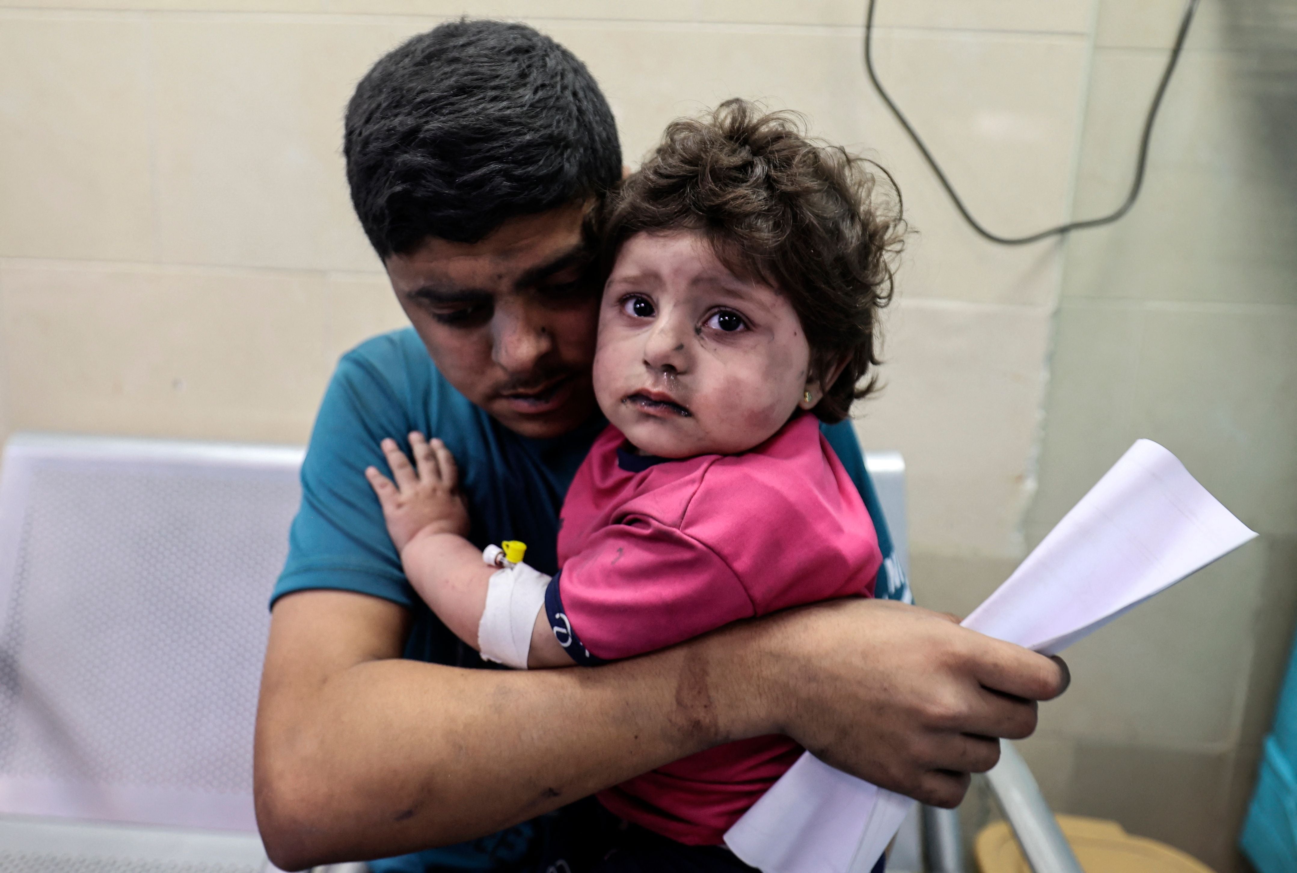 A Palestinian man holds an injured girl awaiting medical care at al-Shifa hospital in Gaza city