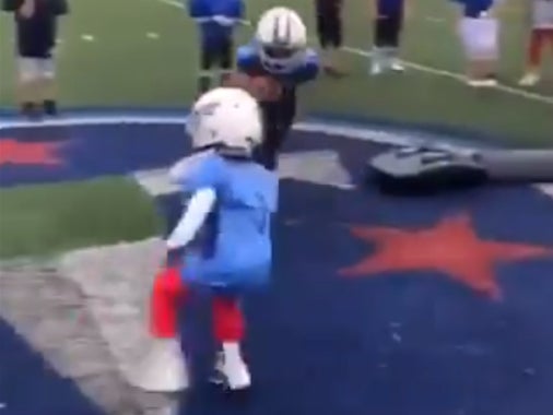 Two small athletes can be seen ahead of a drill and then running directly at each other with helmets on
