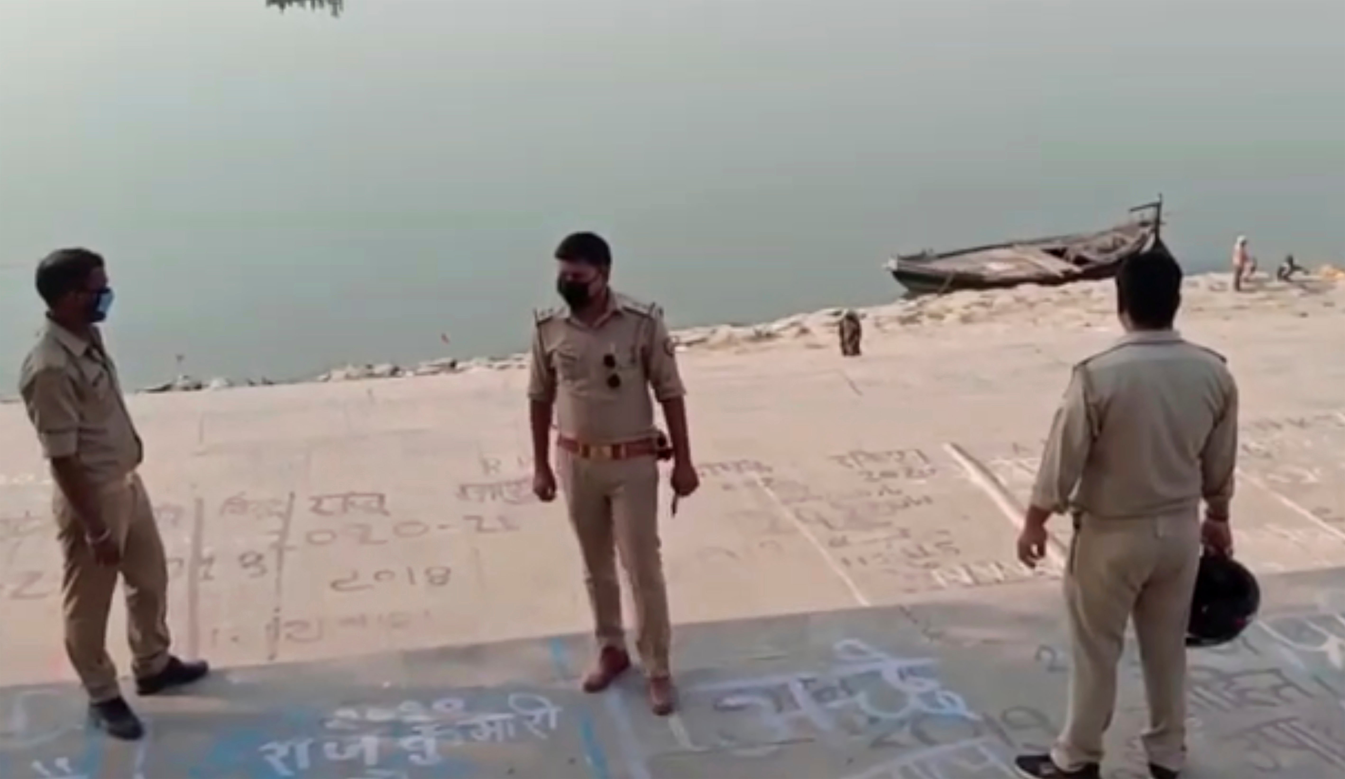 Frame grab from video provided by KK Productions shows police officials stand at the banks of the river where several bodies were found in Ghazipur district in Uttar Pradesh on 11 May, 2021.