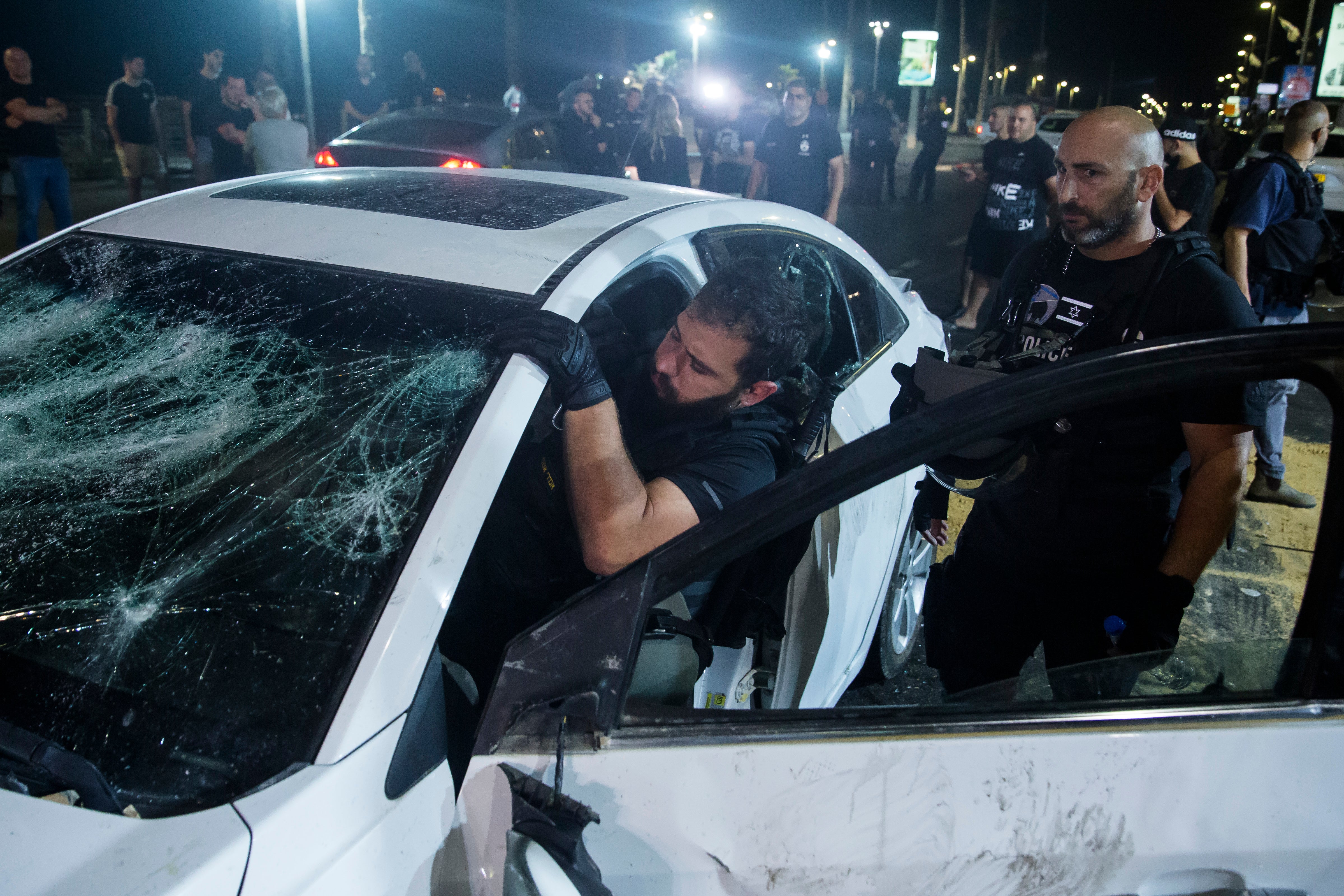 An Israeli police officer inspects the car of an Israeli Arab man who was attacked and seriously injured by a mob in Bat Yam