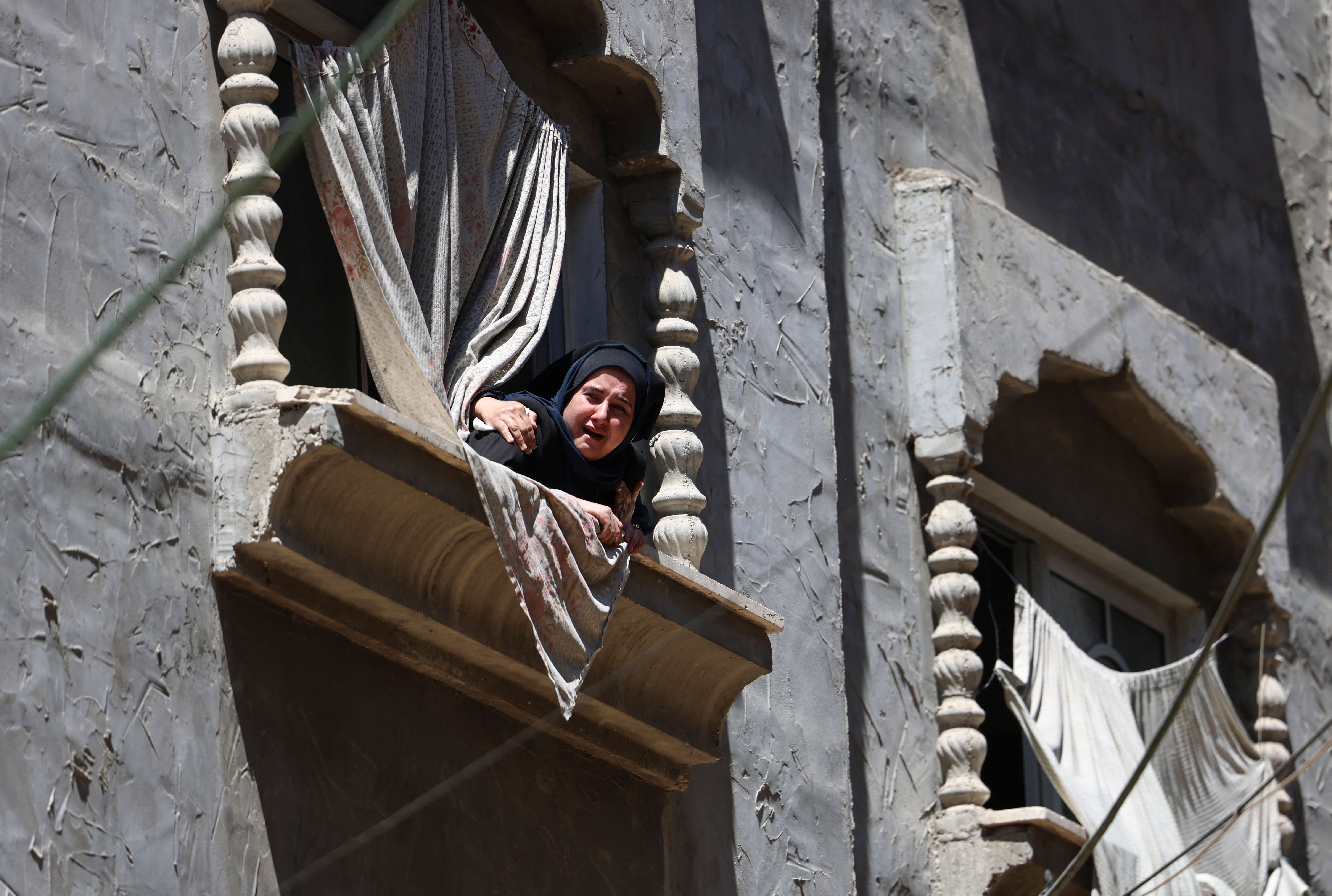 A Palestinian woman watches the funeral procession of Hamas military chief Bassem Issa, killed in an Israeli air strike, in Gaza City, on 13 May