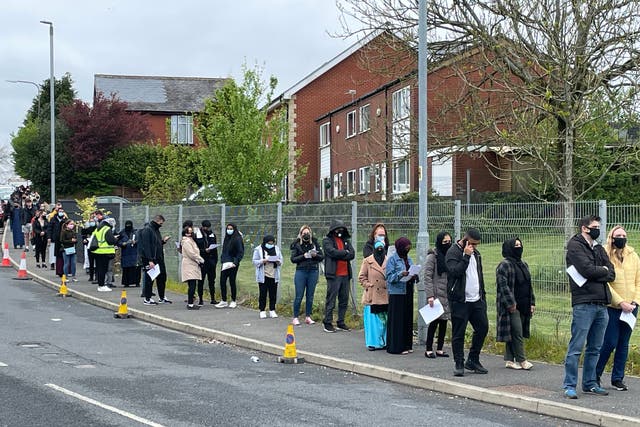 <p>People queue for the vaccination centre at the Essa Academy in Bolton, where the Indian variant has been detected</p>