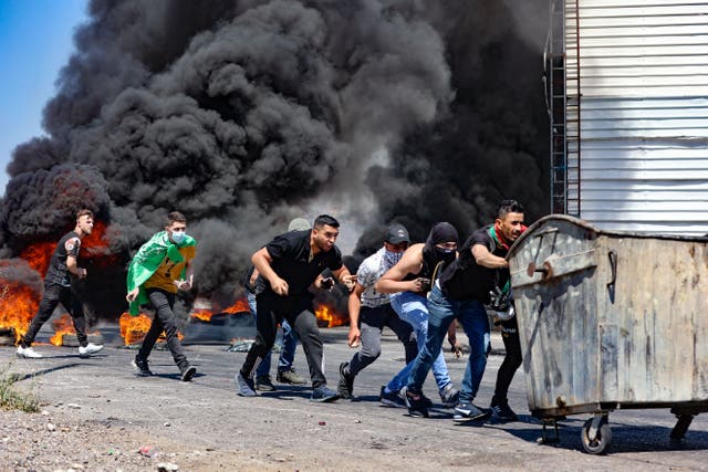 <p>Palestinian youths push a rubbish container used as a barricade, during confrontations with Israeli security forces near the Hawara checkpoint, south of the occupied West Bank city of Nablus</p>