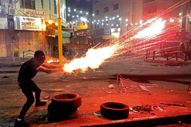 Un manifestante palestino lanza bengalas en medio de enfrentamientos con soldados israelíes en el centro de la ciudad de Hebrón en Cisjordania