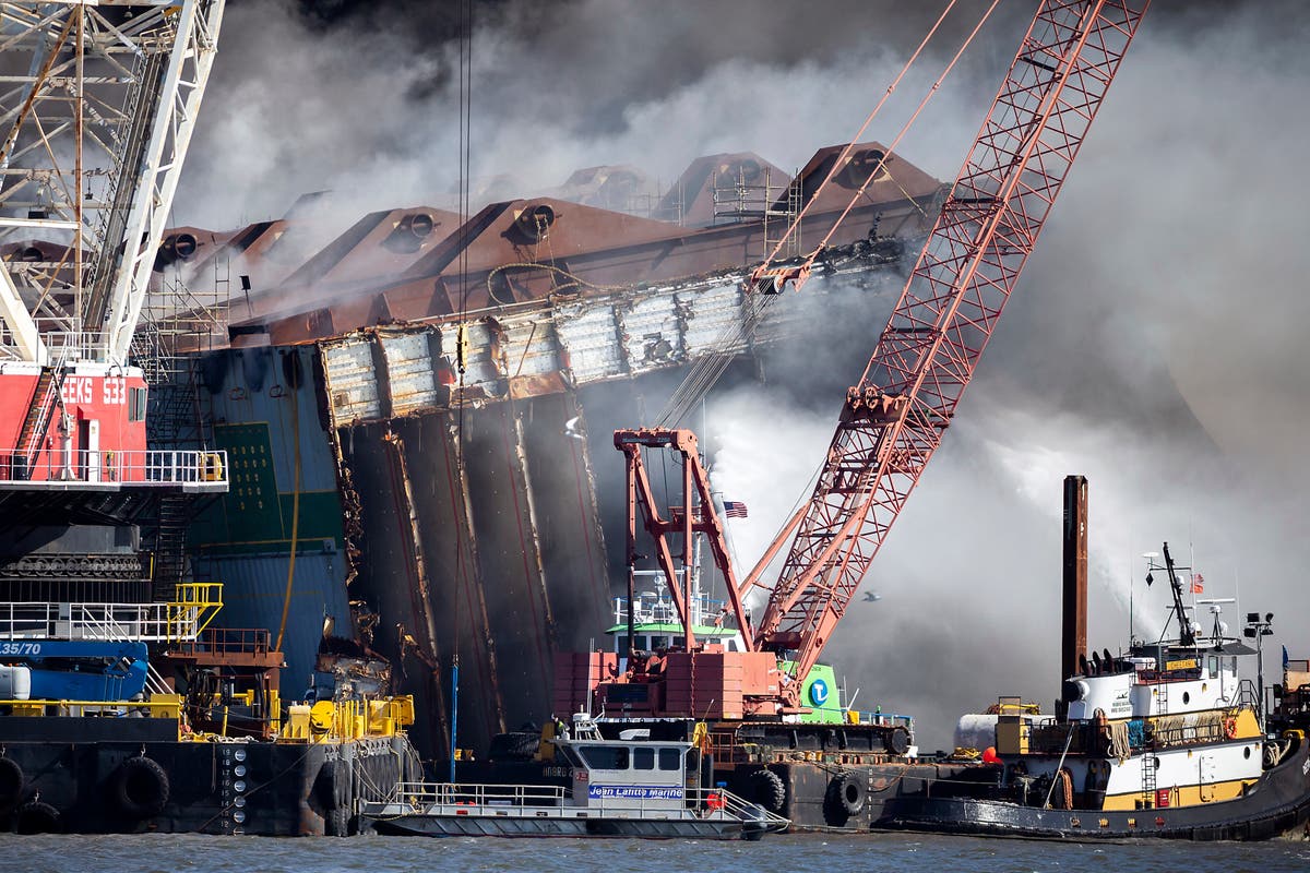 Damage assessment begins on overturned cargo ship after fire