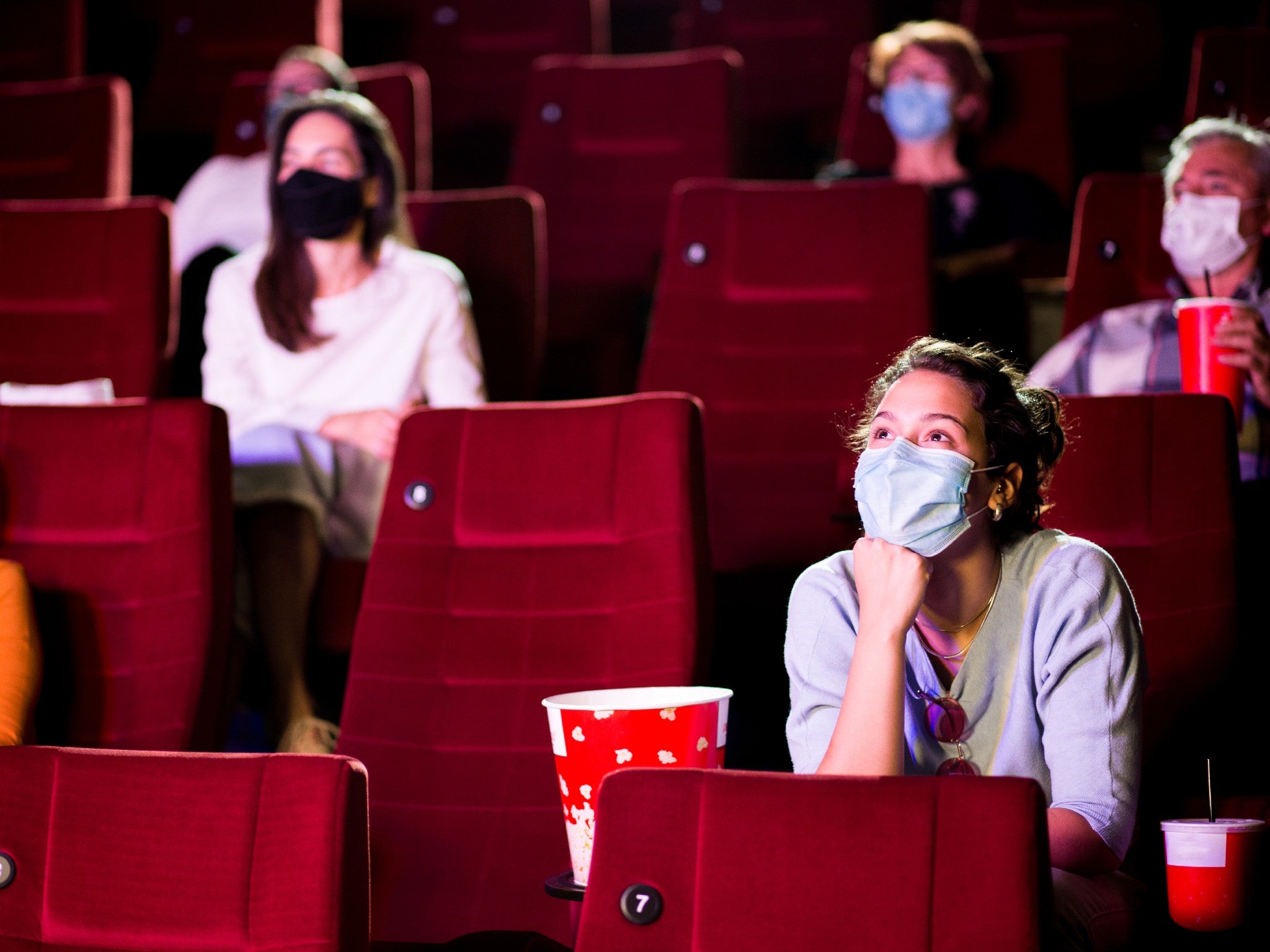 Audience at the cinema wearing protective masks and sitting in a socially-distanced manner