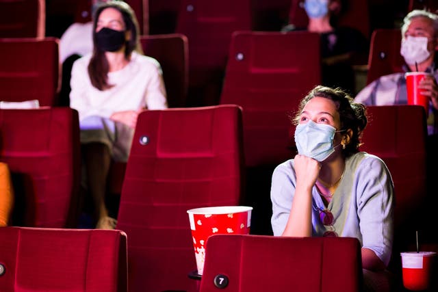 Audience at the cinema wearing protective masks and sitting in a socially-distanced manner