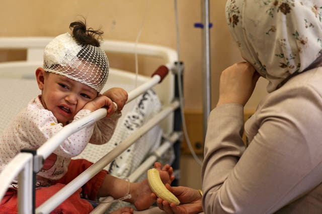 Una madre palestina se sienta con su hija, que resultó herida durante los ataques aéreos israelíes durante la noche en la Franja de Gaza, mientras recibe tratamiento en el hospital al-Shifa de la ciudad de Gaza.
