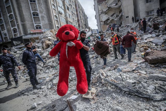 Un palestino sostiene un oso de peluche entre los escombros de las casas destruidas después de un ataque aéreo israelí en la ciudad de Gaza.