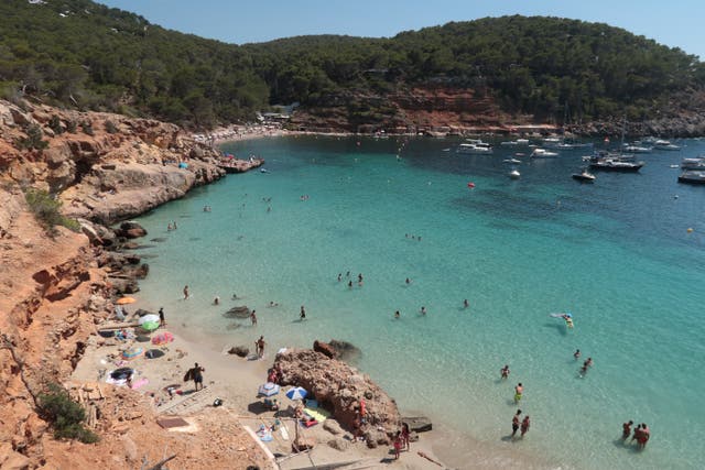 <p>Bathers relax at Cala Saladeta beach on the island of Ibiza</p>
