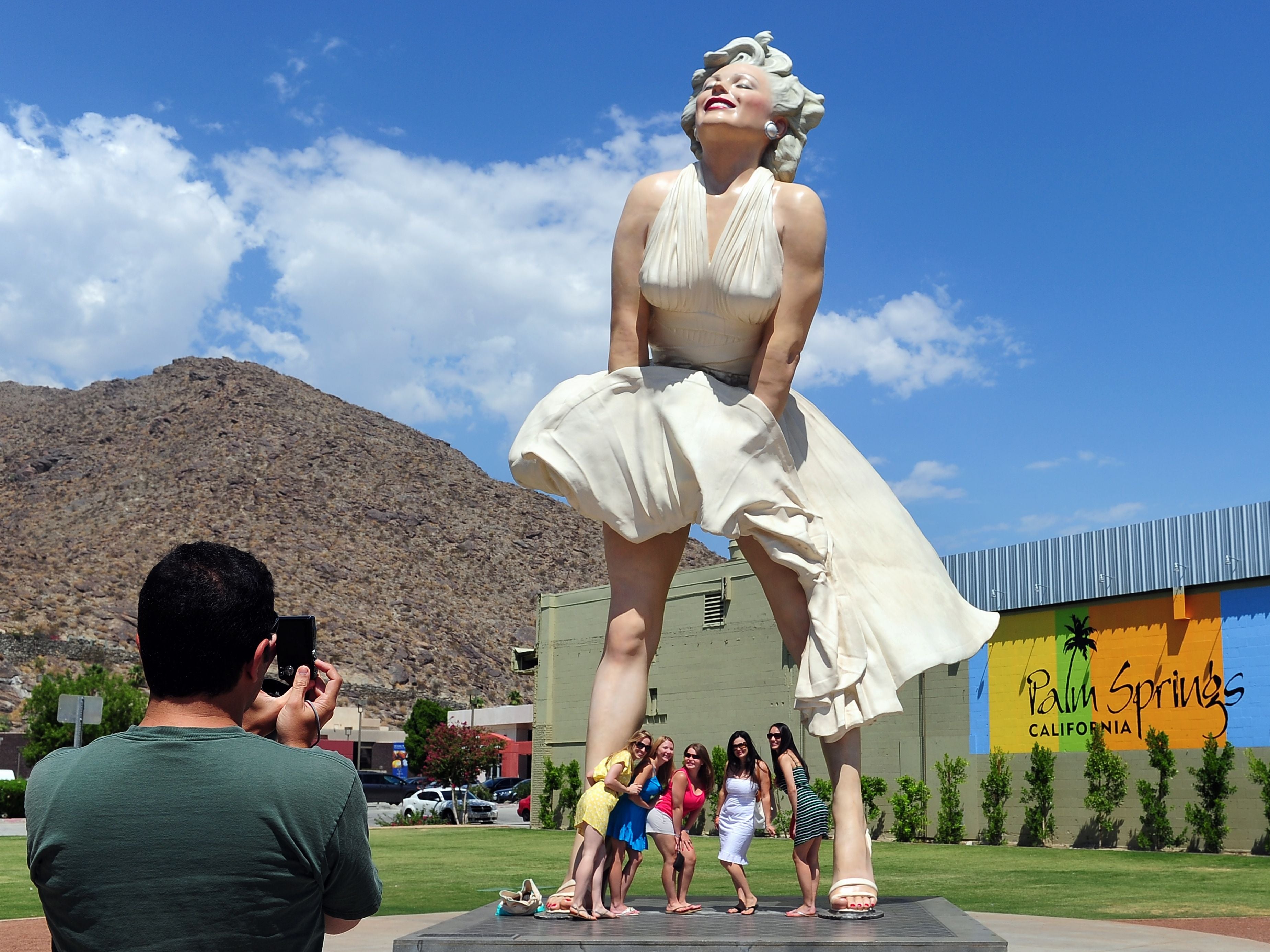 Women pose for a photo beneath the 'Forever Marilyn' statue of actress Marilyn Monroe in Palm Springs, California, on August 4, 2012