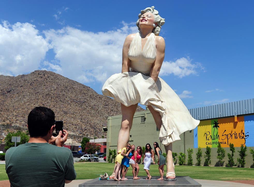<p>Women pose for a photo beneath the 'Forever Marilyn' statue of actress Marilyn Monroe in Palm Springs, California, on August 4, 2012</p>