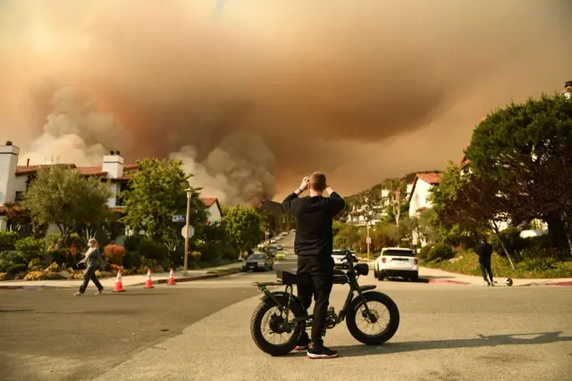<p>A teenage boy takes a photo of the fire sweeping certain parts of Los Angeles</p>