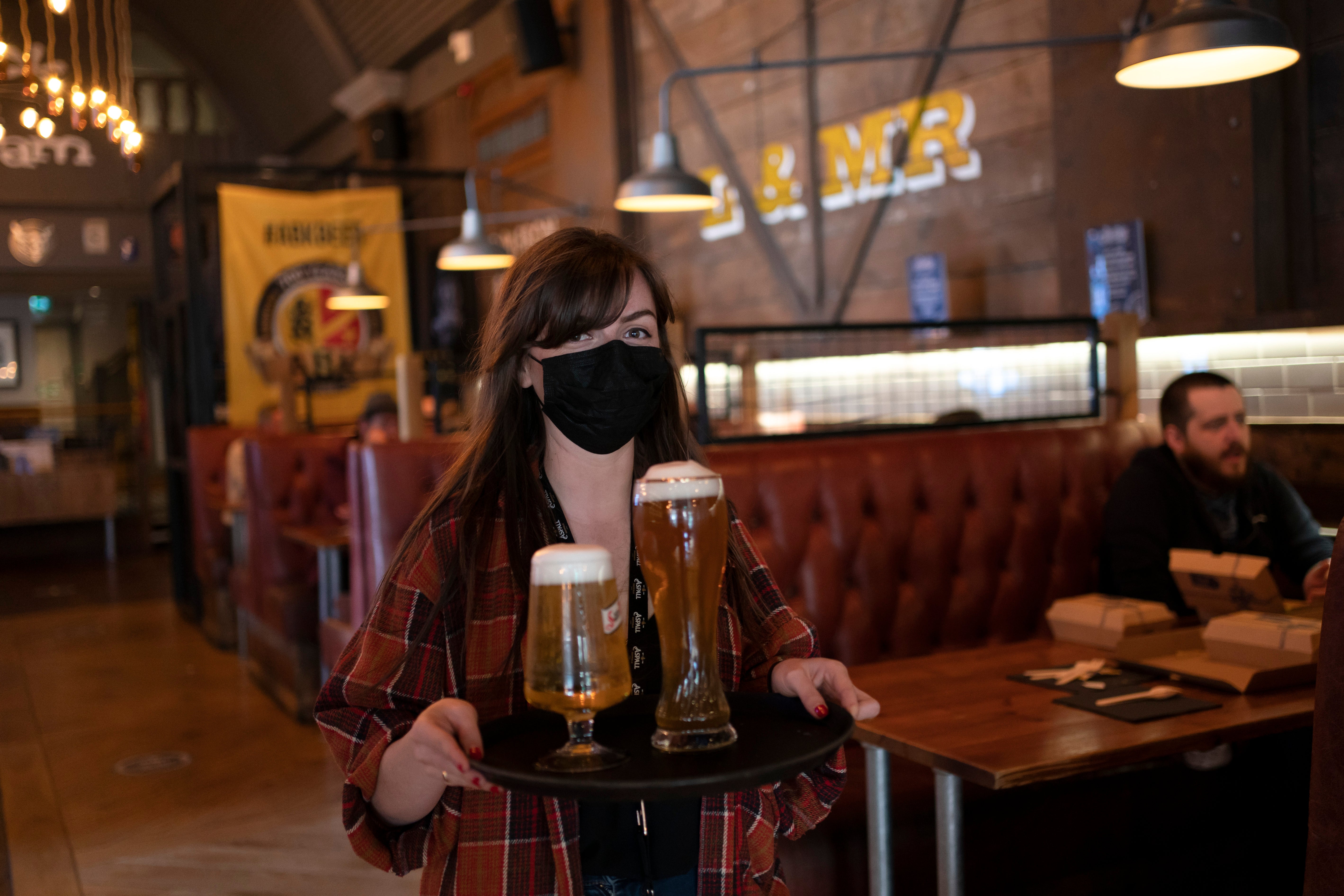 A member of staff serves drinks in a pub in Liverpool as pubs, cafes and restaurants in England reopened indoors