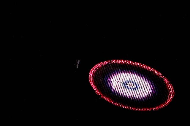 US plastic artist Peter Coffin's "Flying Saucer" --a 7-meter, LED-studded, SMS-controlled flying saucer and lifted by a helicopter-- overflies Ipanema beach, on May 23, 2009