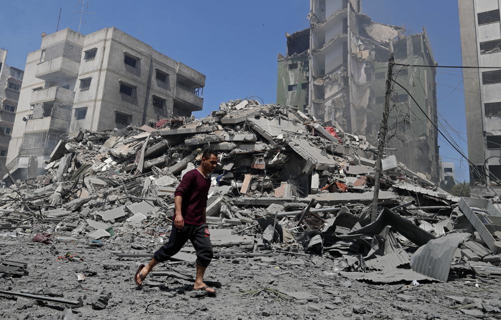 A man walks past the rubble of the Yazegi residential building that was destroyed by an Israeli airstrike, in Gaza City, Sunday, 16 May