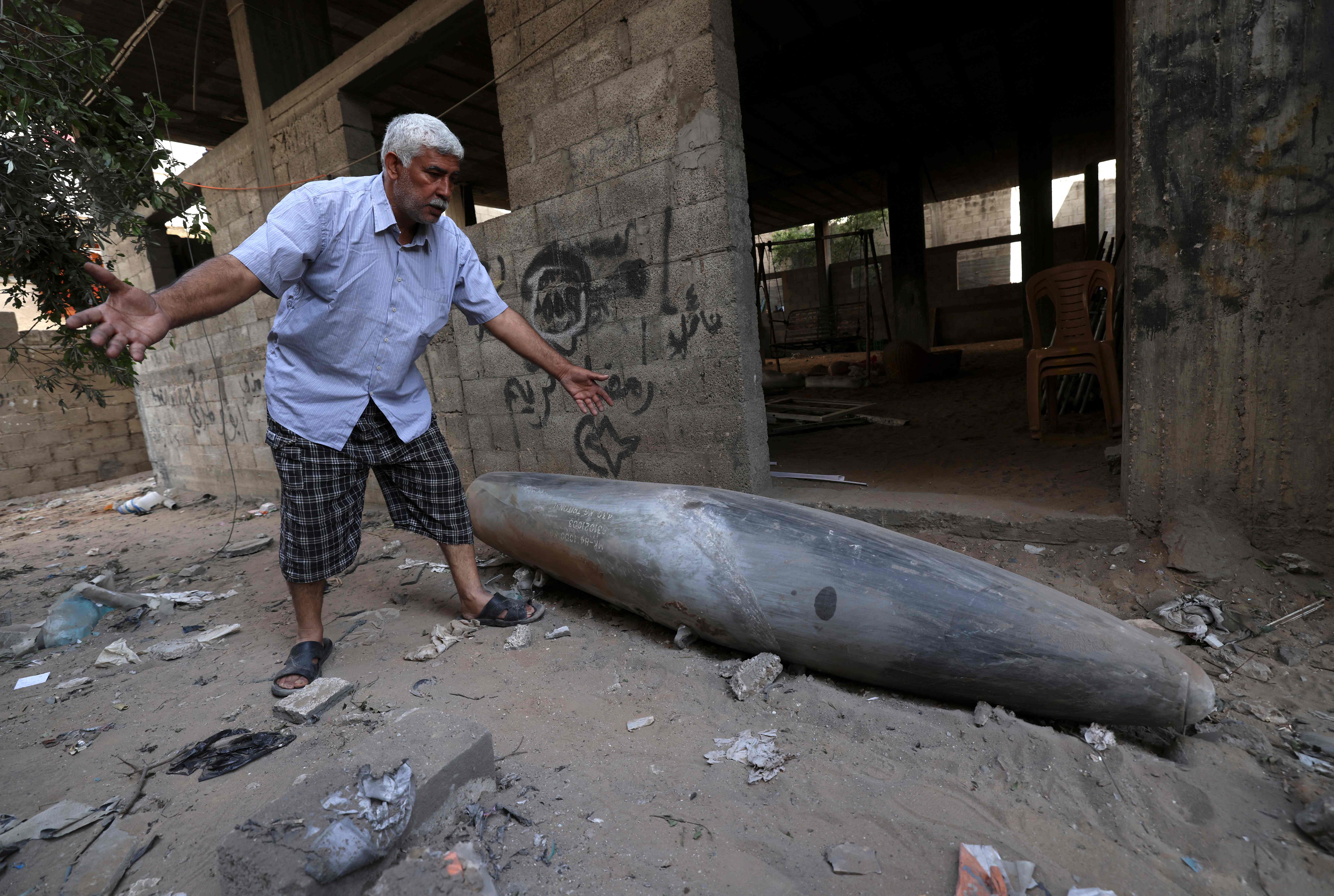 A Palestinian man reacts as he looks at an unexploded bomb dropped by an Israeli F-16 warplane on Gaza City's Rimal neighbourhood
