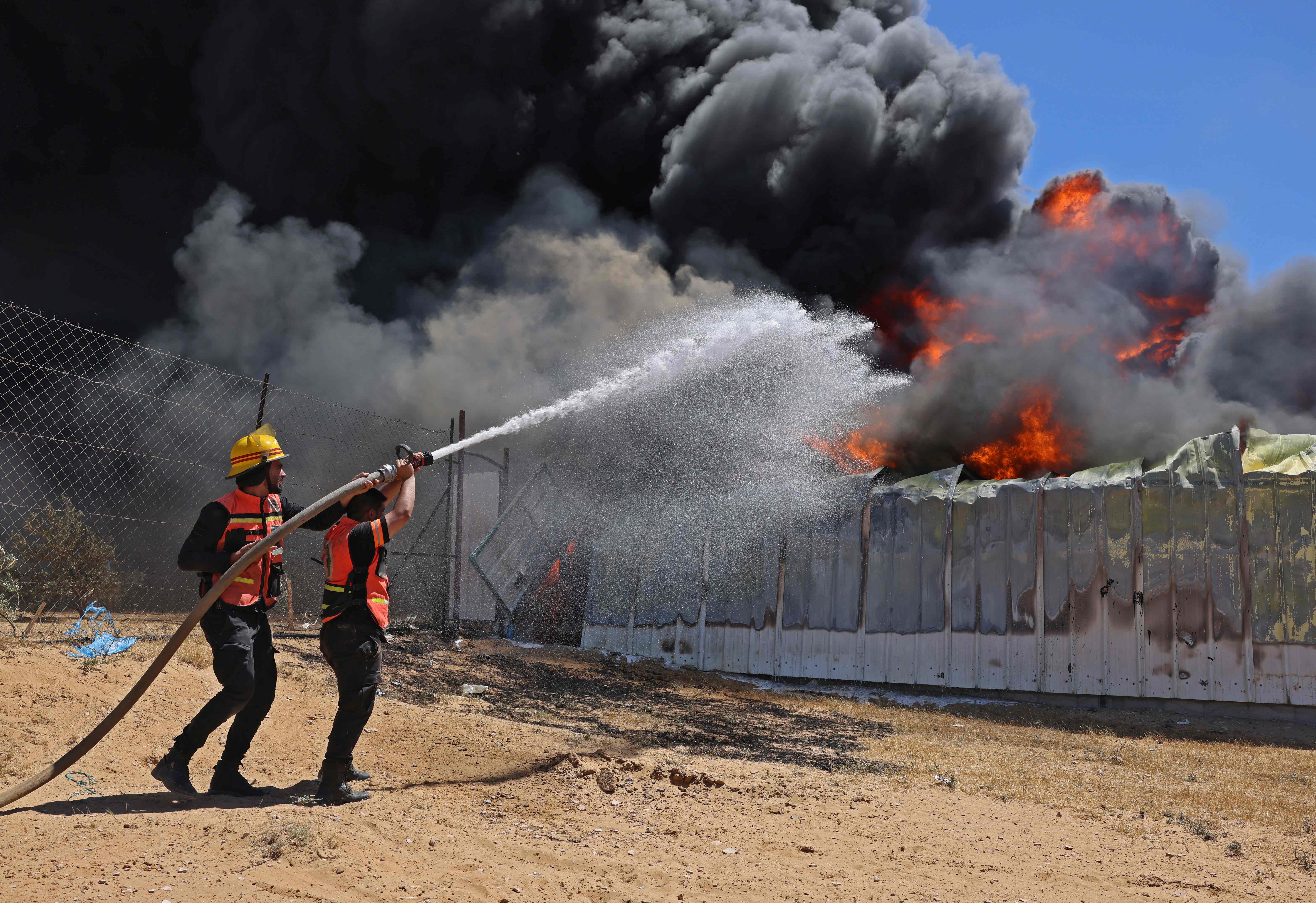 Members of the Palestinian Civil Defence extinguish a fire in a paint warehouse that was hit by an Israeli artillery shell on eastern Rafah, in the southern Gaza Strip