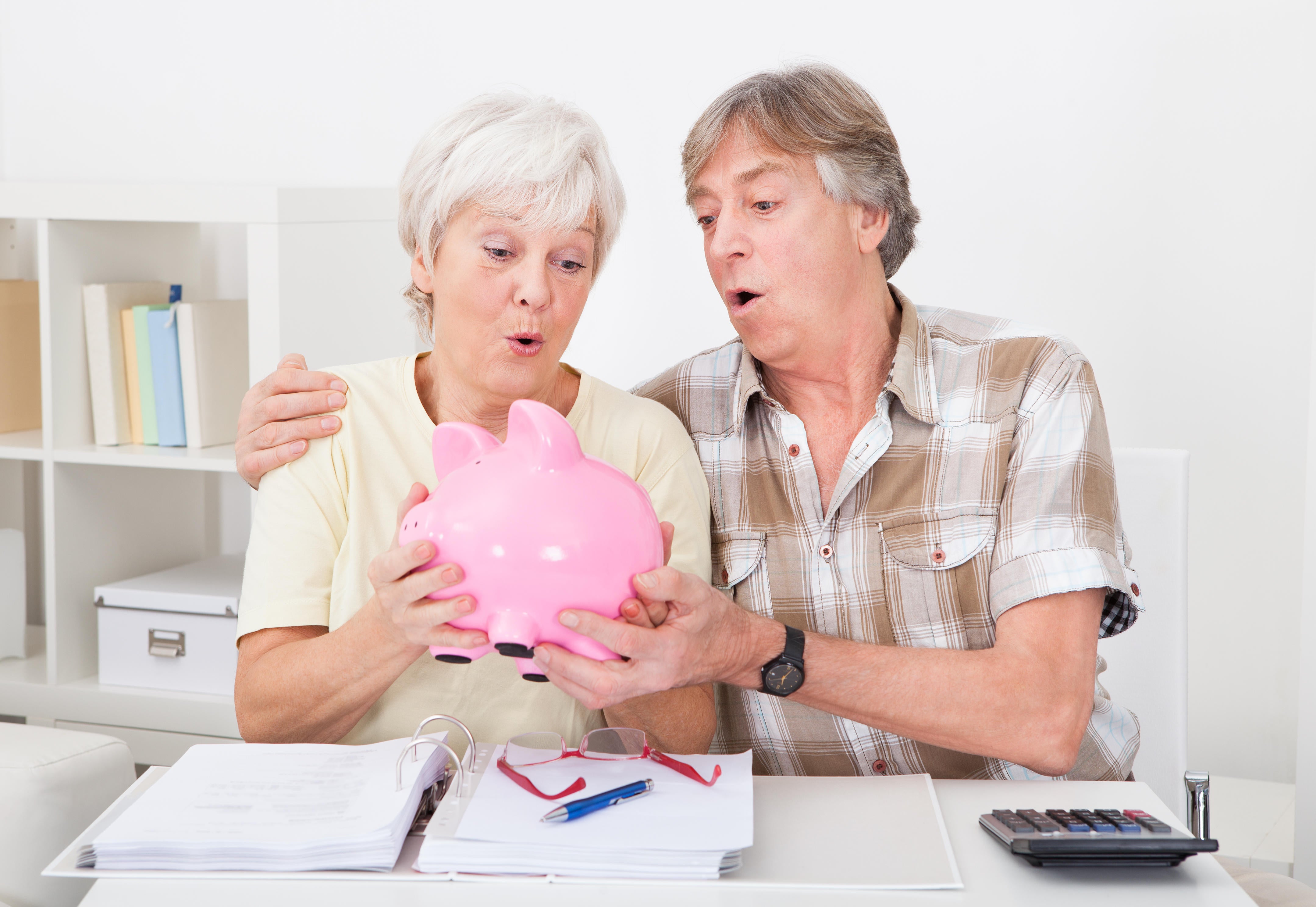 Senior Couple Saving Money In The Pink Piggybank